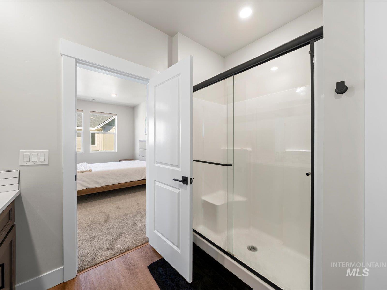 Full bathroom featuring wood finished floors, vanity, recessed lighting, a shower stall, and ensuite bathroom