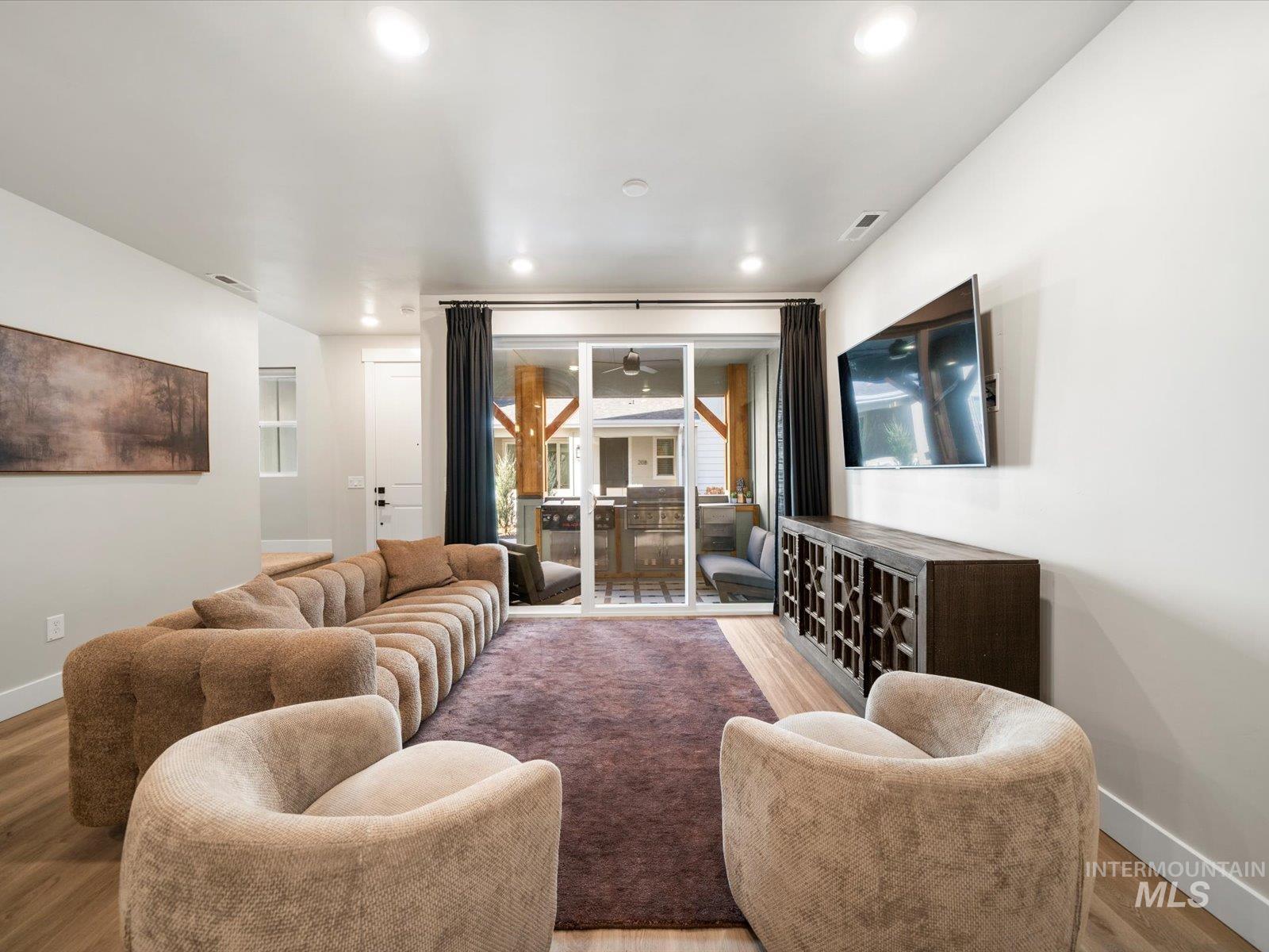 Living room with wood finished floors, a ceiling fan, and recessed lighting