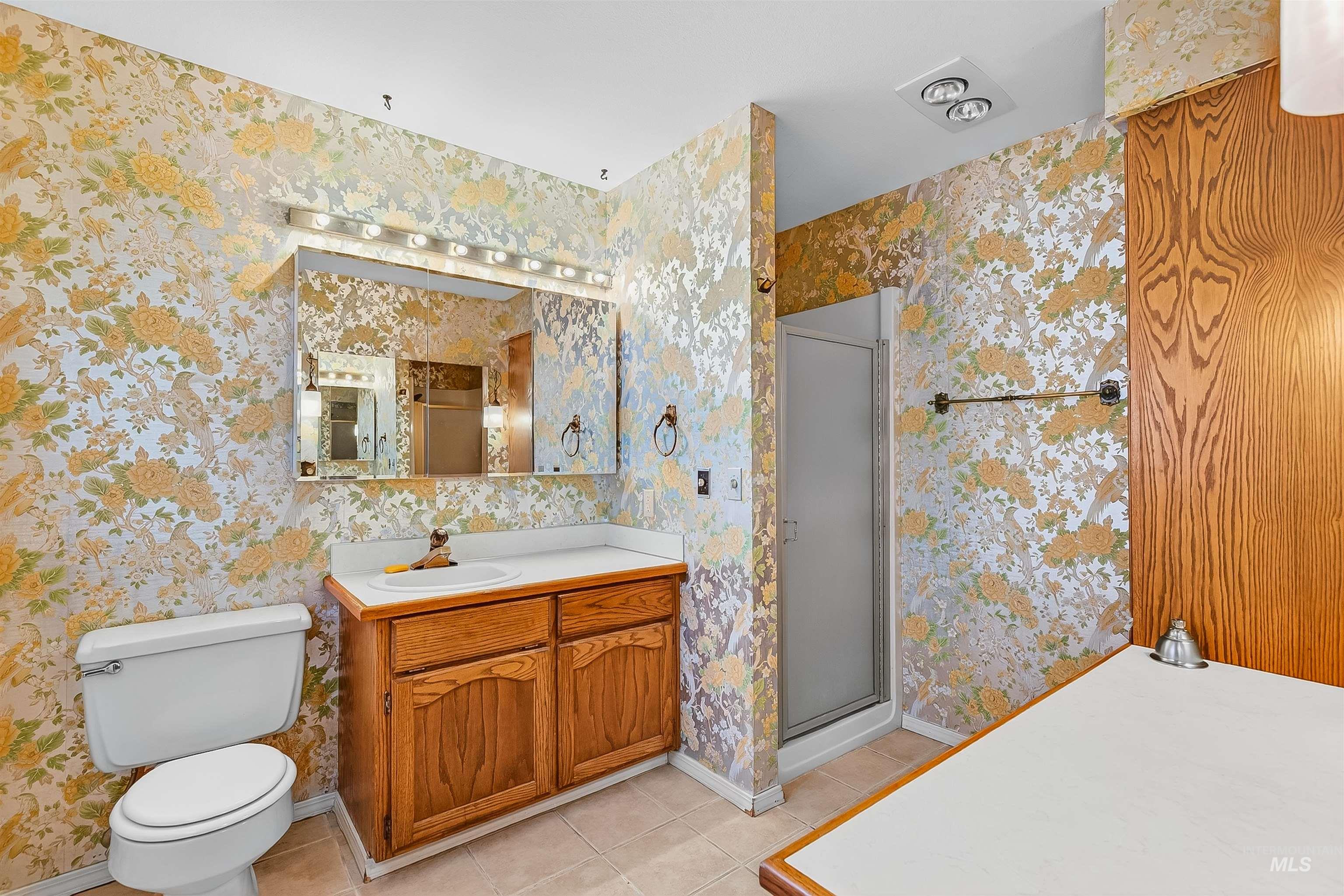 Full bathroom with light tile patterned floors, a shower stall, vanity, and wallpapered walls