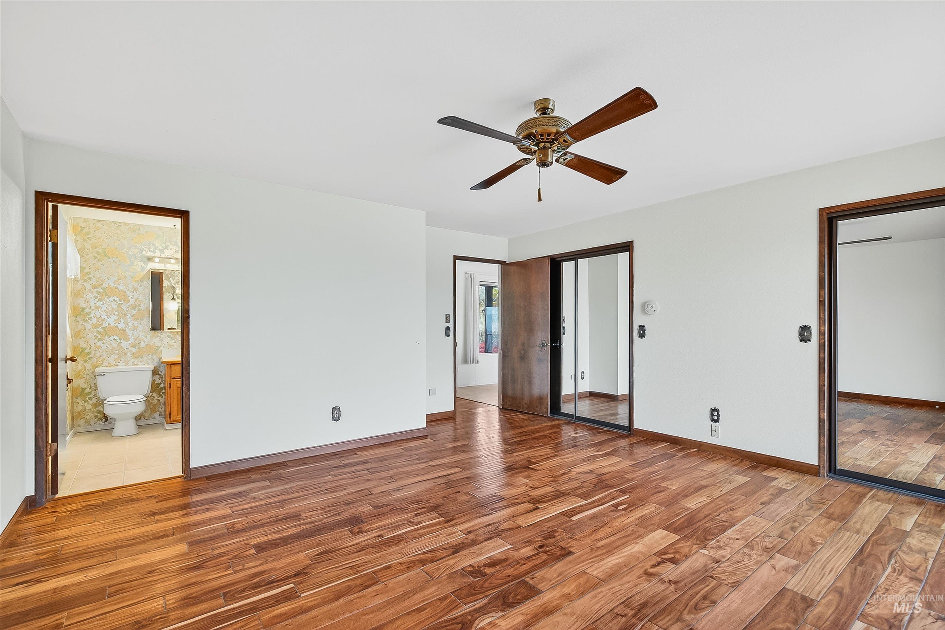 Unfurnished bedroom featuring light wood-style floors, a ceiling fan, and ensuite bathroom