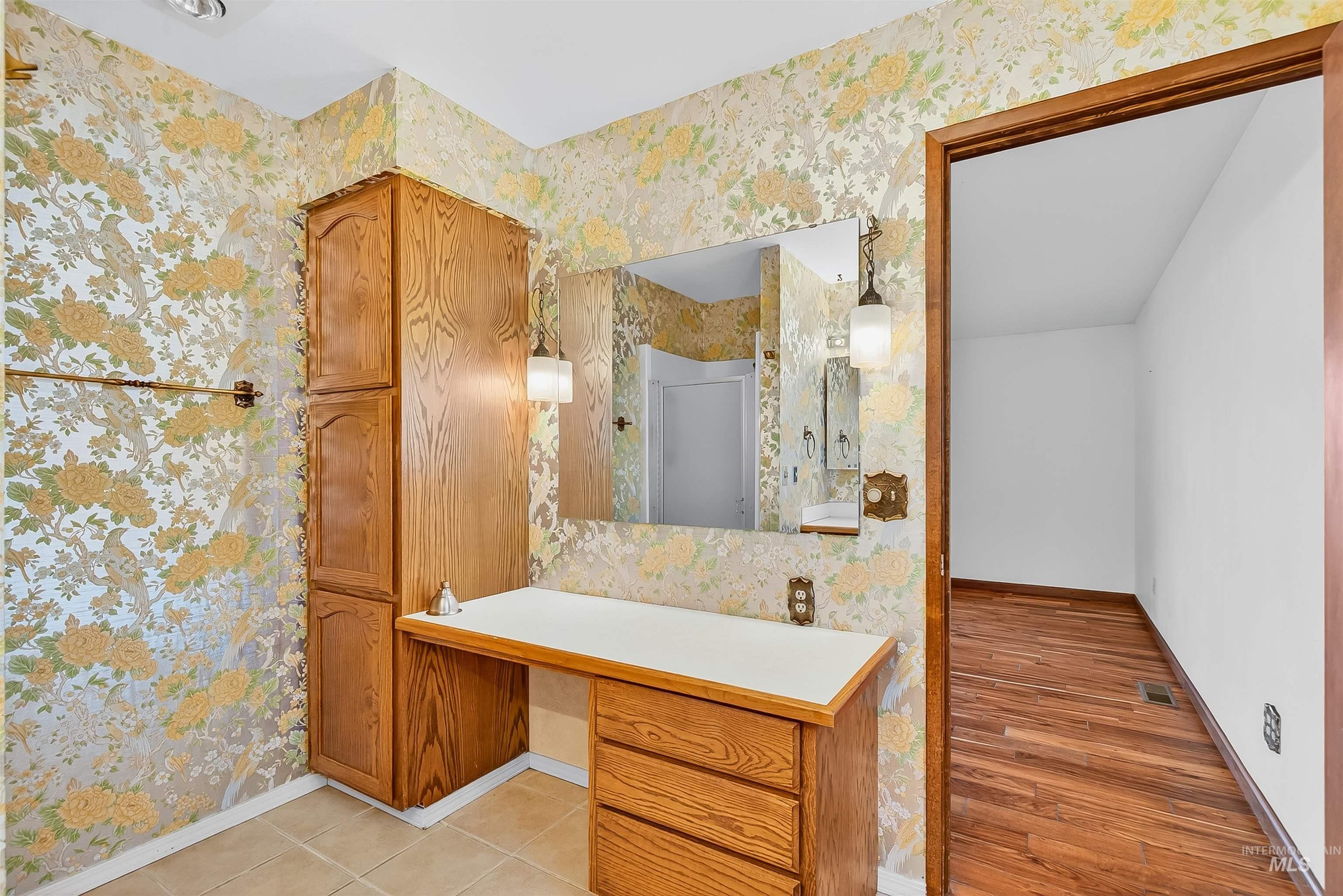 Bathroom with wallpapered walls, vanity, a shower, and light tile patterned floors