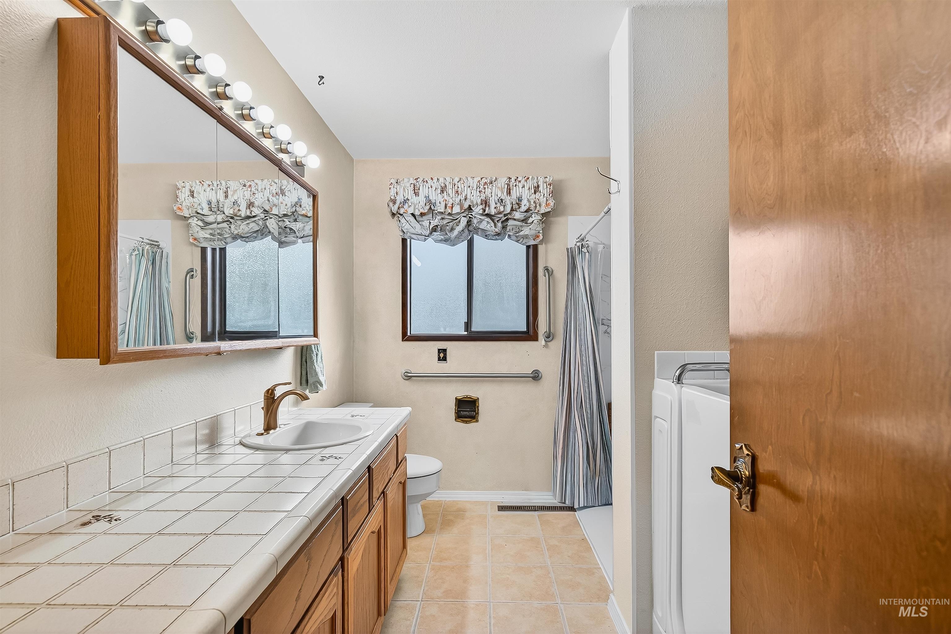 Bathroom featuring vanity, light tile patterned floors, and curtained shower