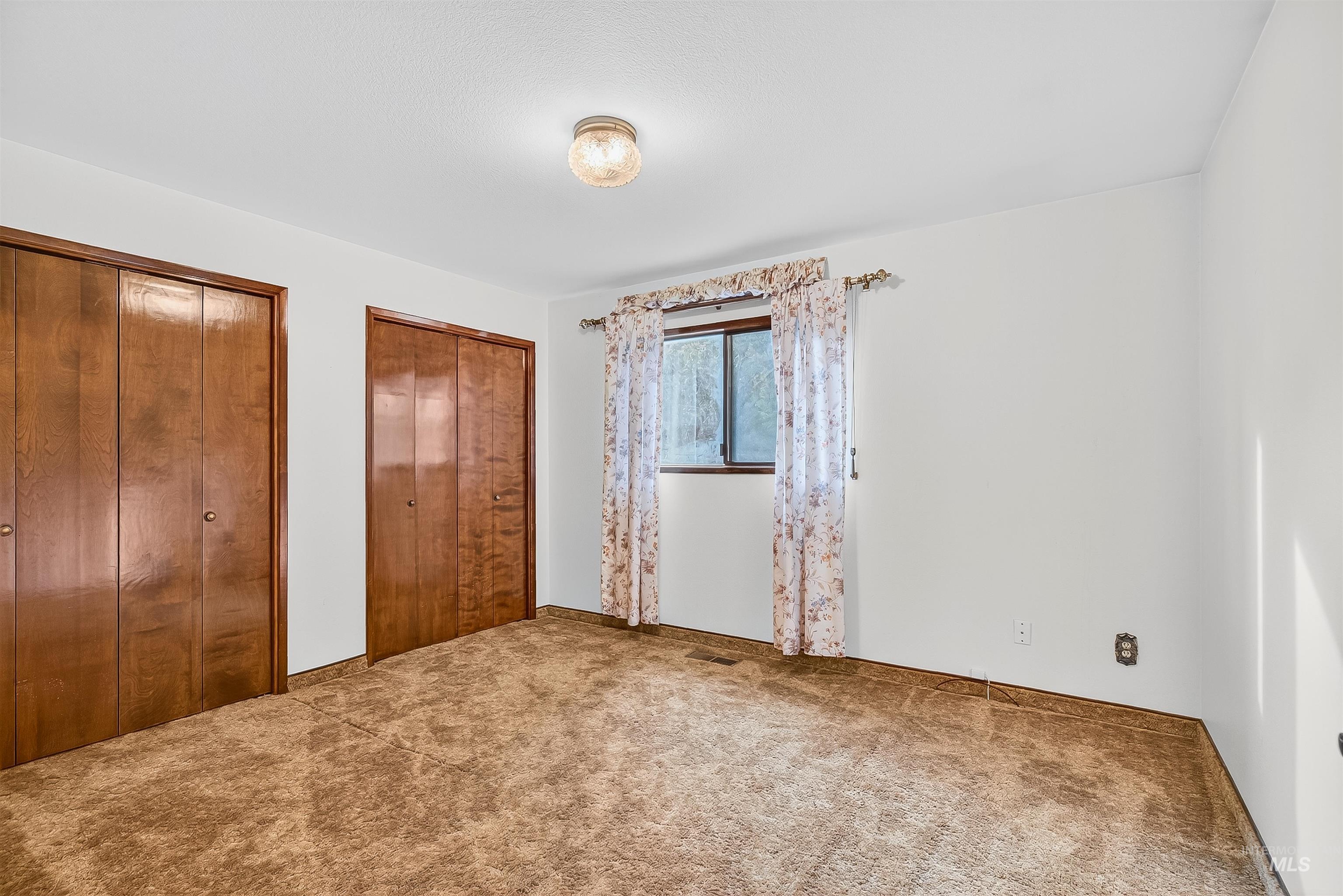 Unfurnished bedroom with multiple closets and carpet flooring