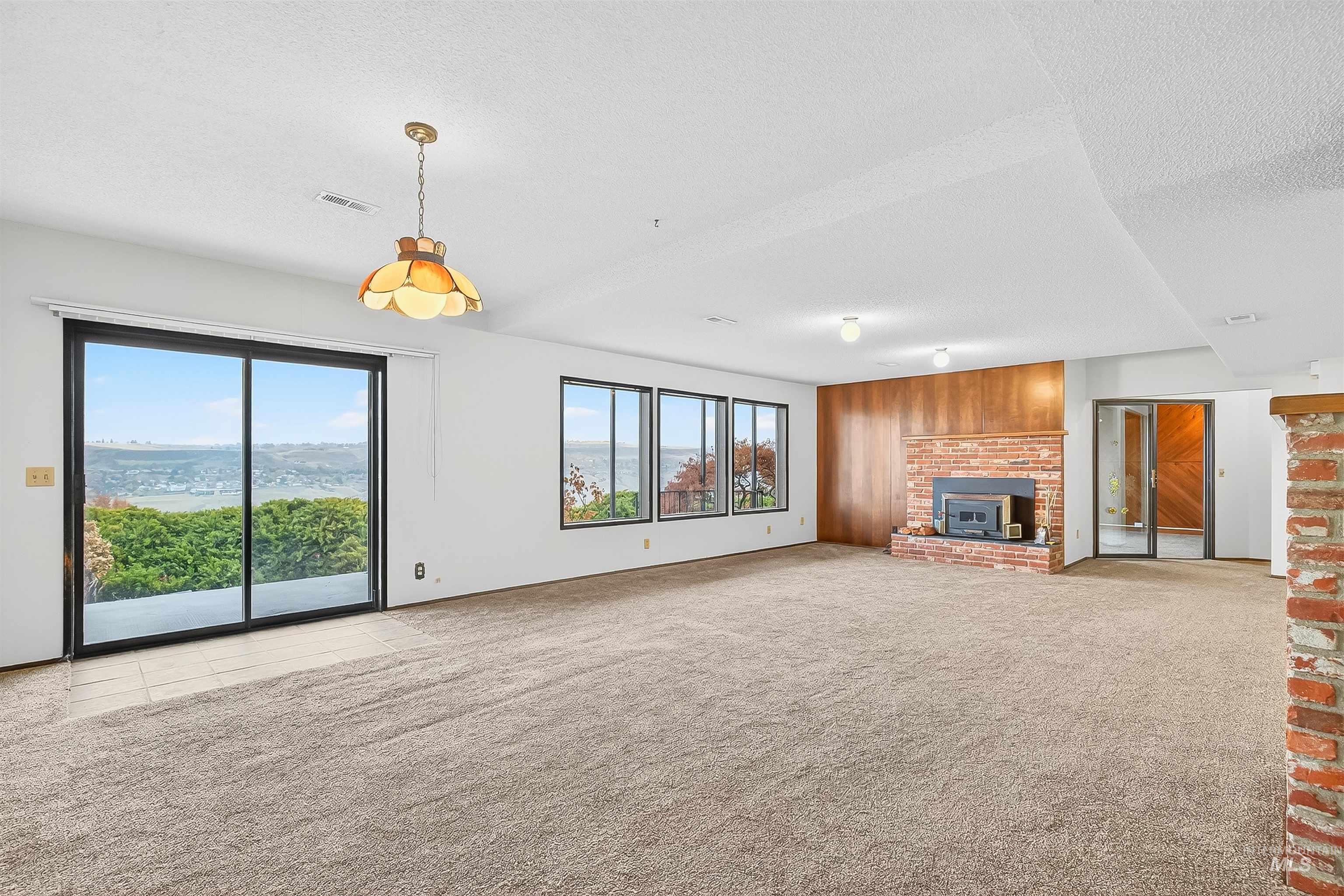 Unfurnished living room featuring light colored carpet and a textured ceiling