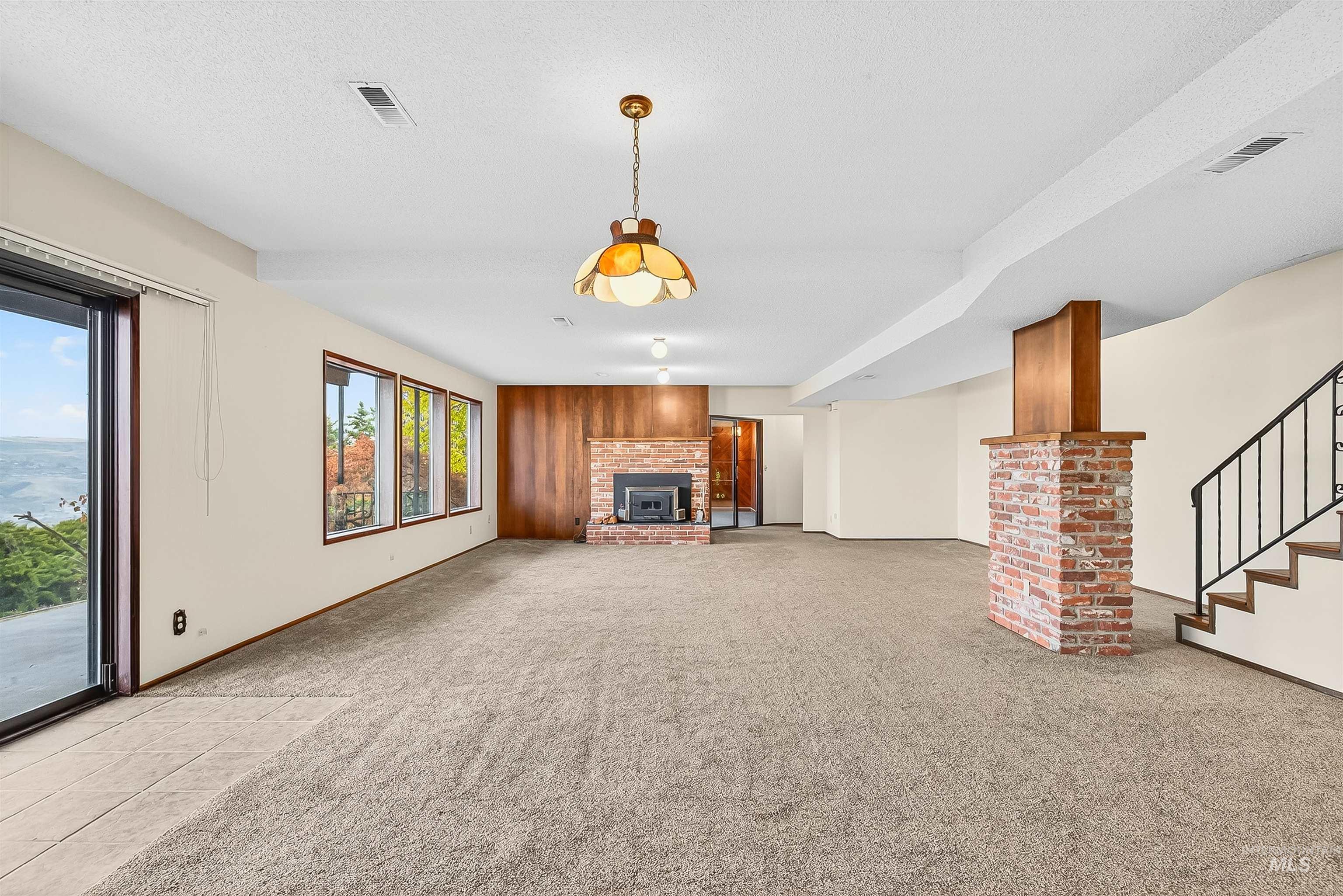 Unfurnished living room featuring a fireplace, light carpet, stairway, and light tile patterned flooring