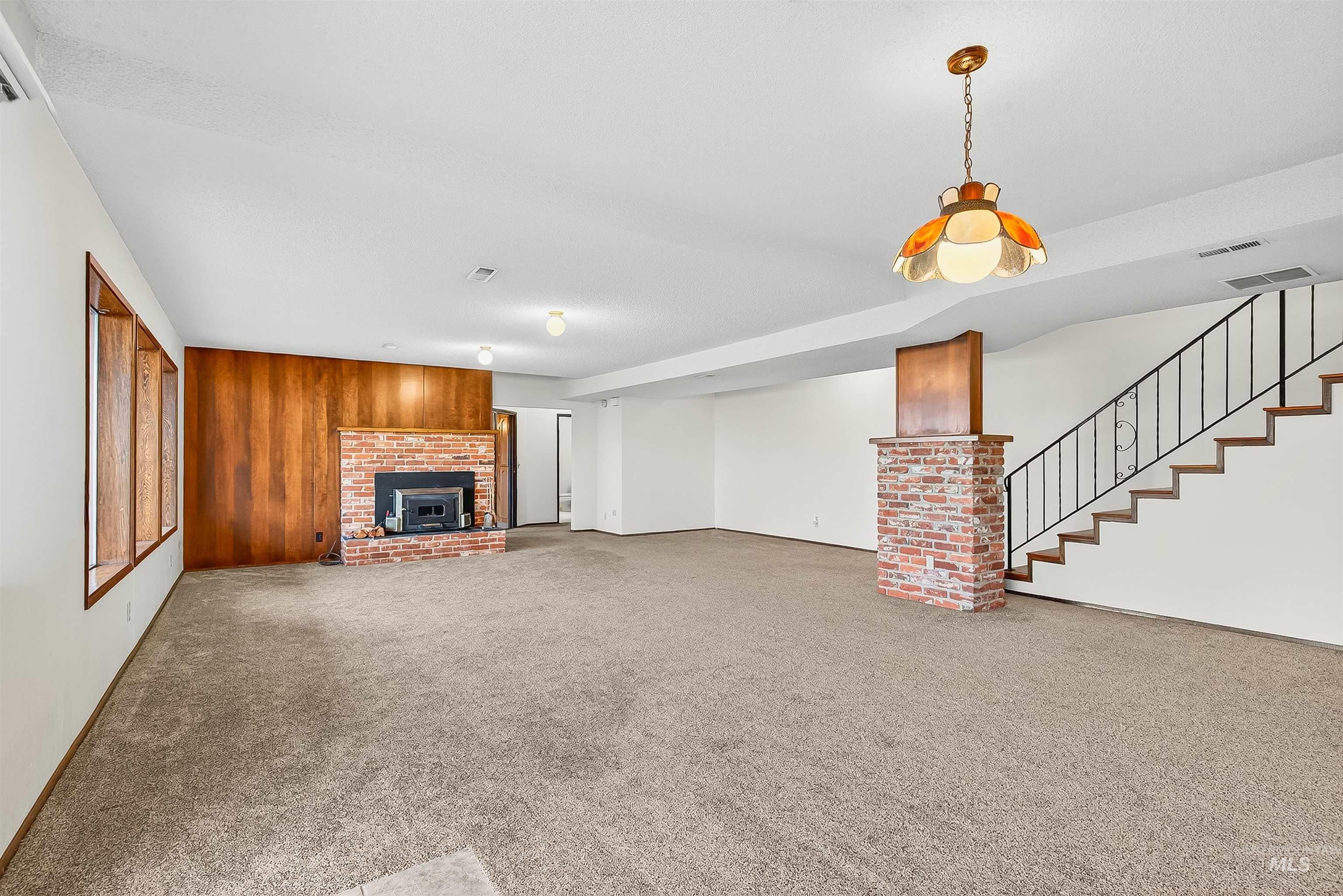 Unfurnished living room with carpet flooring and stairway