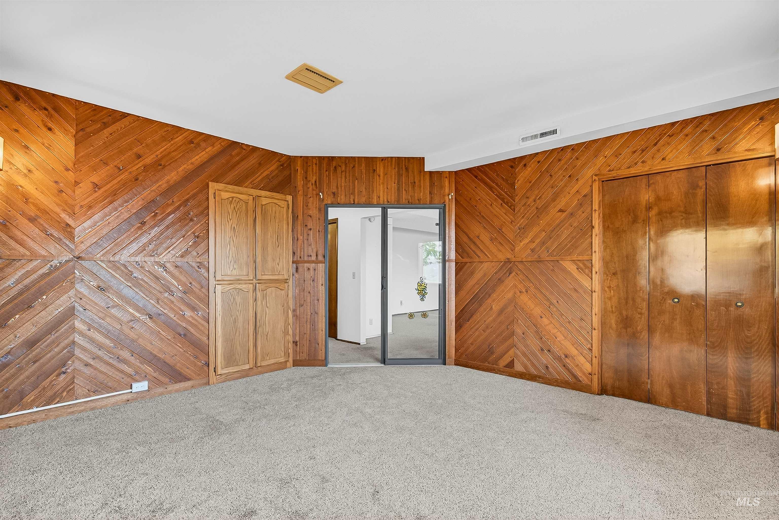 Unfurnished bedroom featuring wood walls, carpet flooring, and a closet