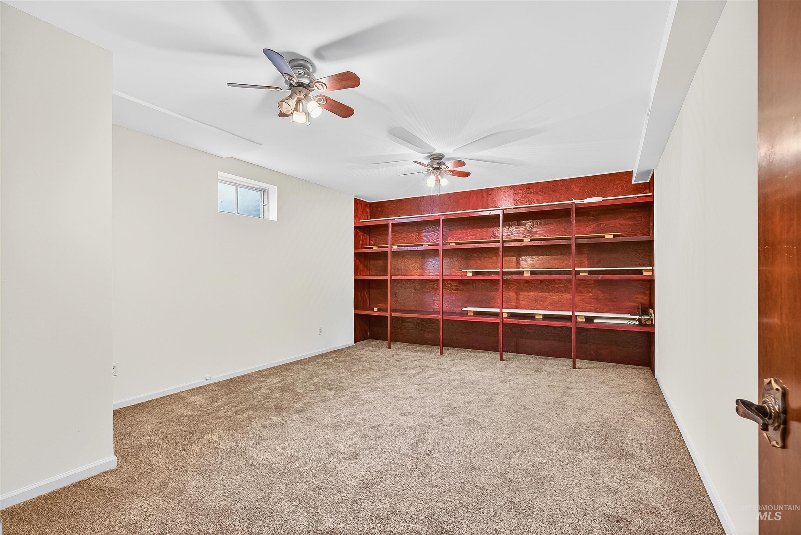 Unfurnished office with a ceiling fan, light colored carpet, and built in shelves
