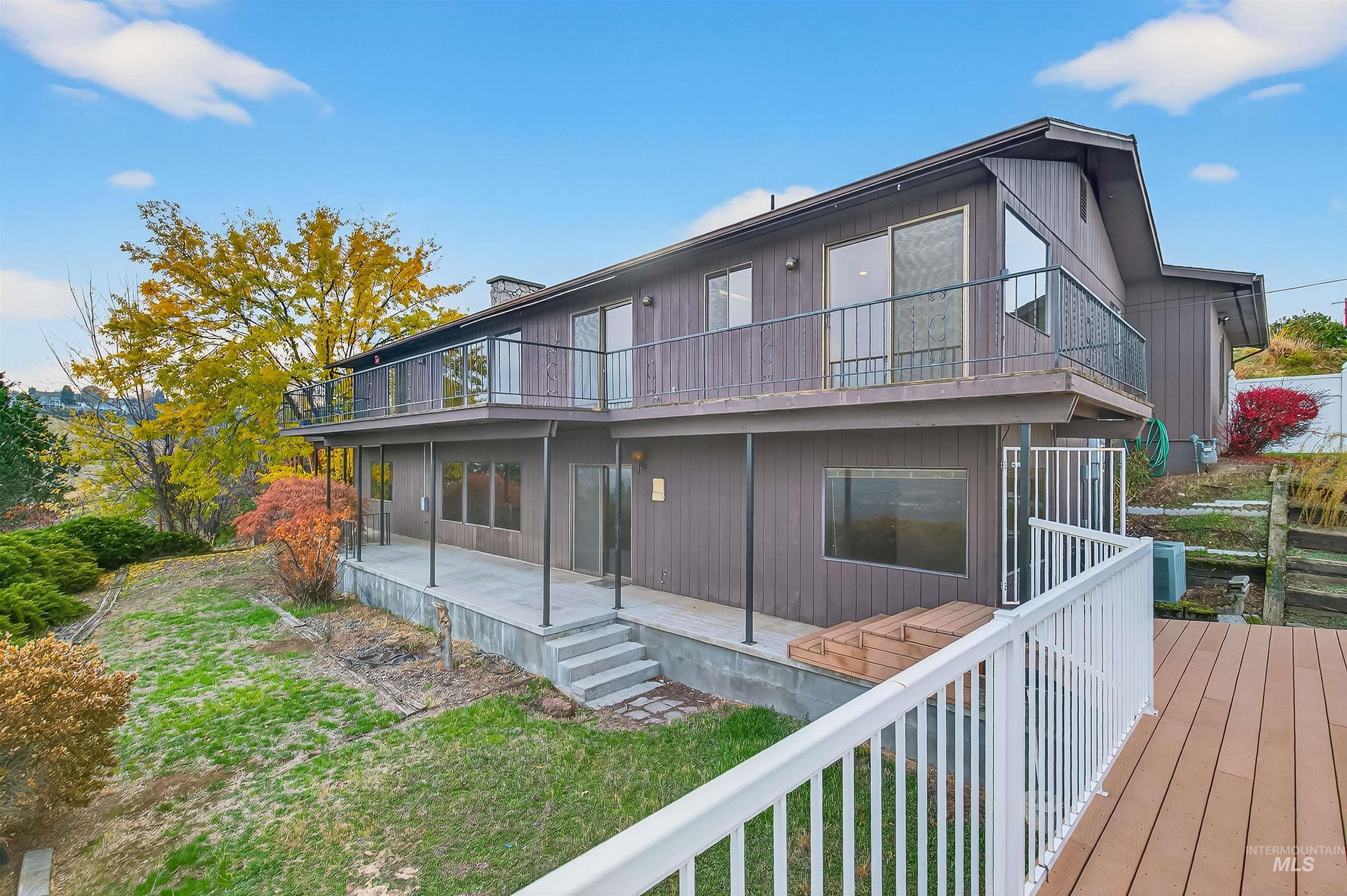 Back of house with a balcony, a lawn, and covered porch
