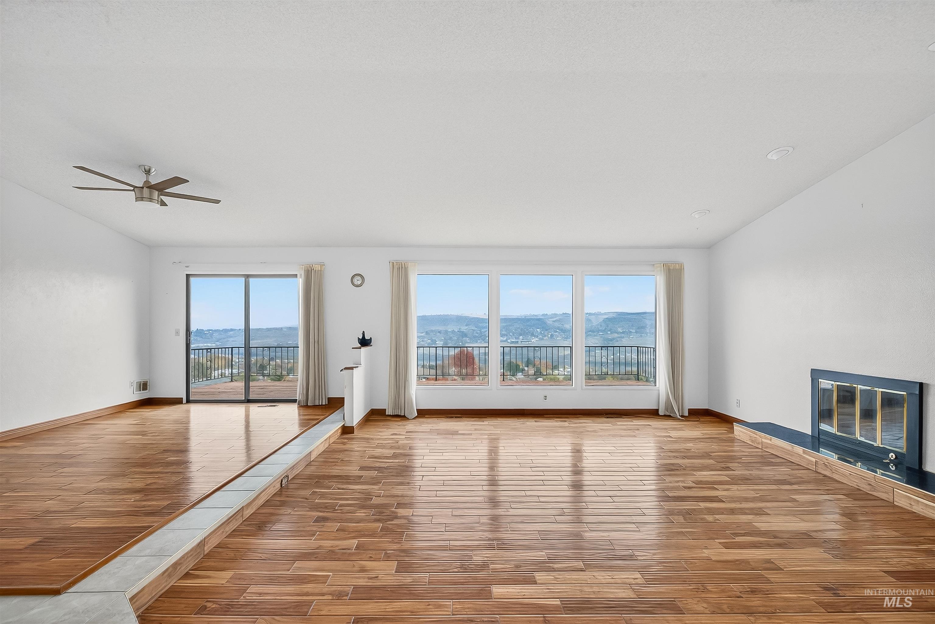 Unfurnished living room with a glass covered fireplace, light wood-style flooring, and a ceiling fan