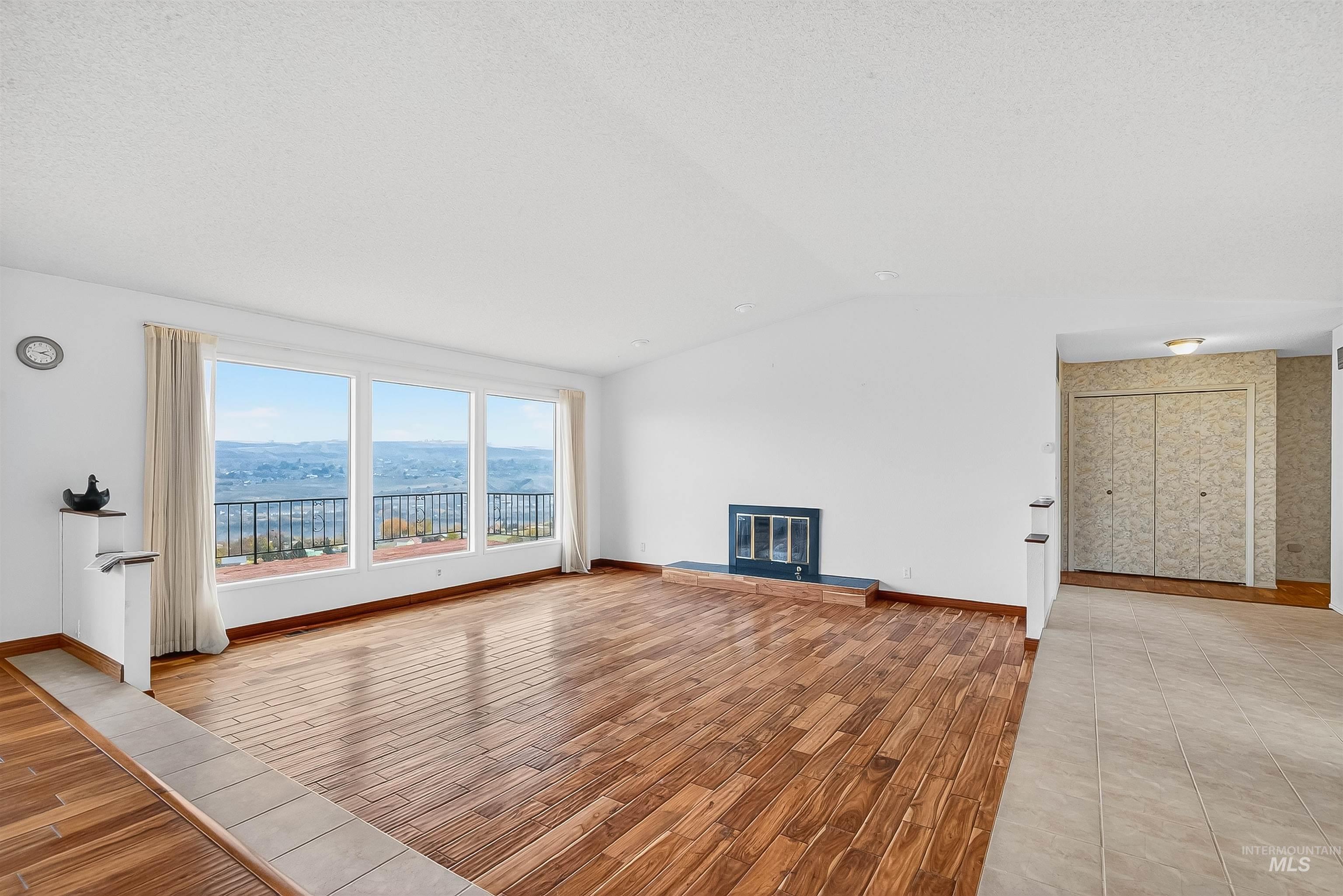 Unfurnished living room featuring light wood-style flooring, a glass covered fireplace, and vaulted ceiling