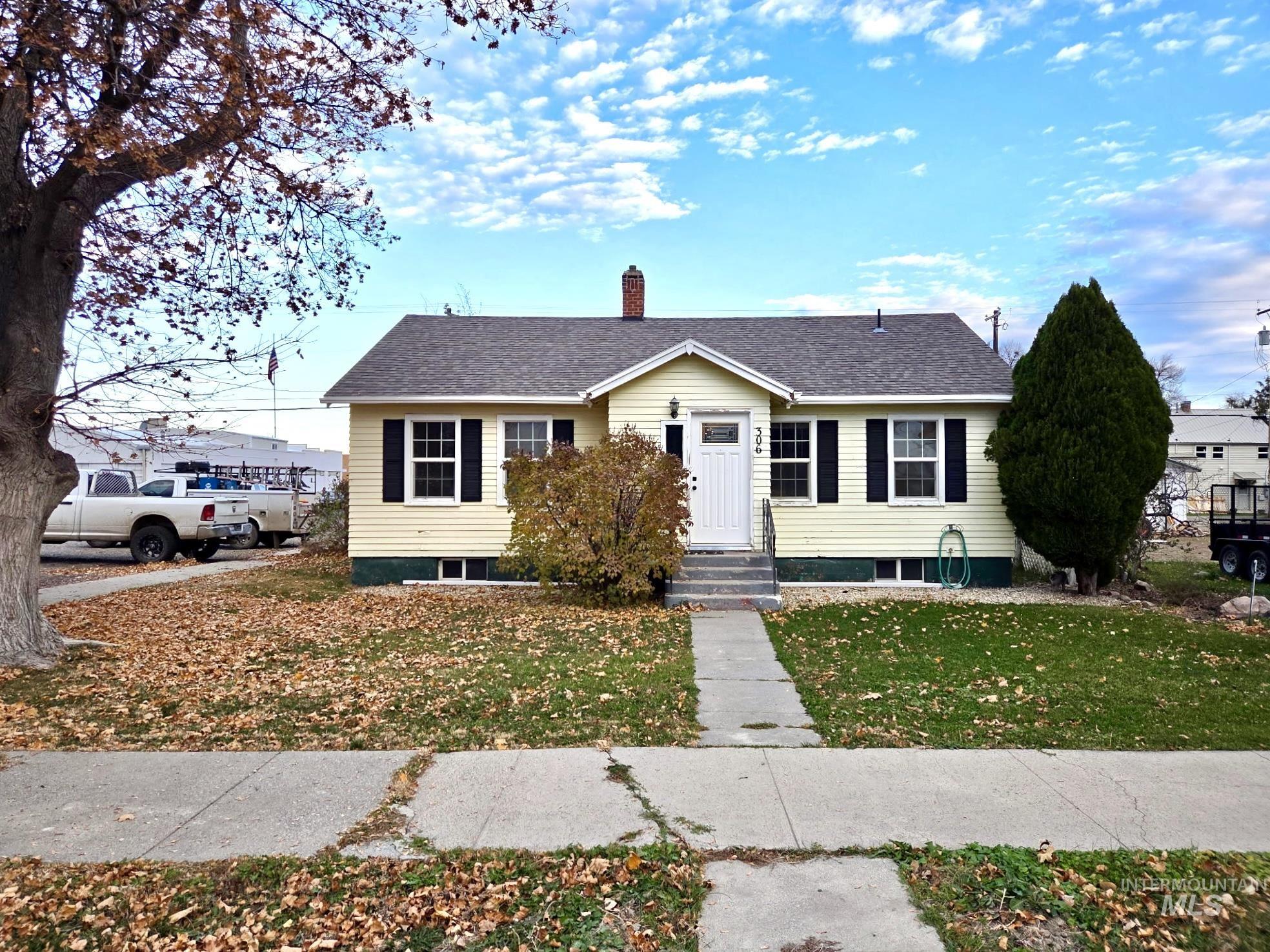 View of front facade featuring a chimney, a front lawn, roof with shingles, and entry steps