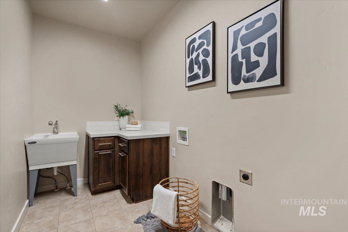 Laundry room with light tile patterned floors, washer hookup, electric dryer hookup, and cabinet space