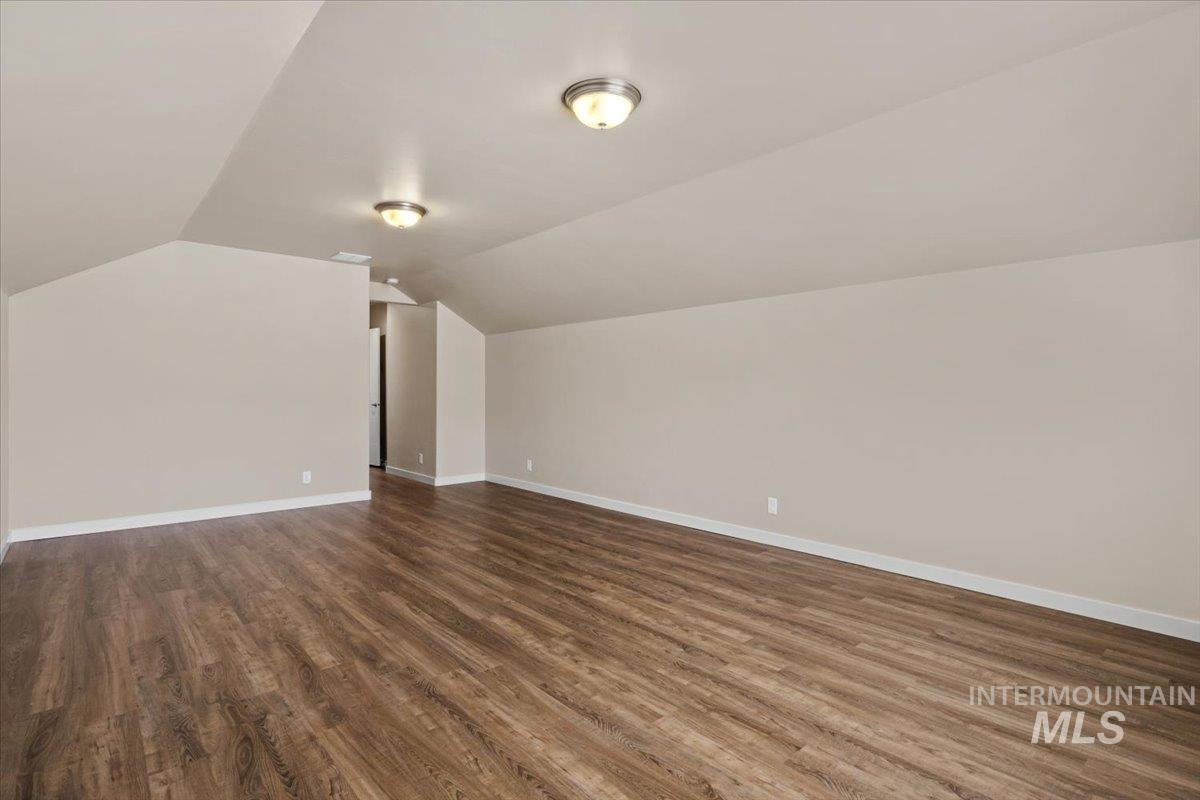 Bonus room with lofted ceiling and dark wood-type flooring