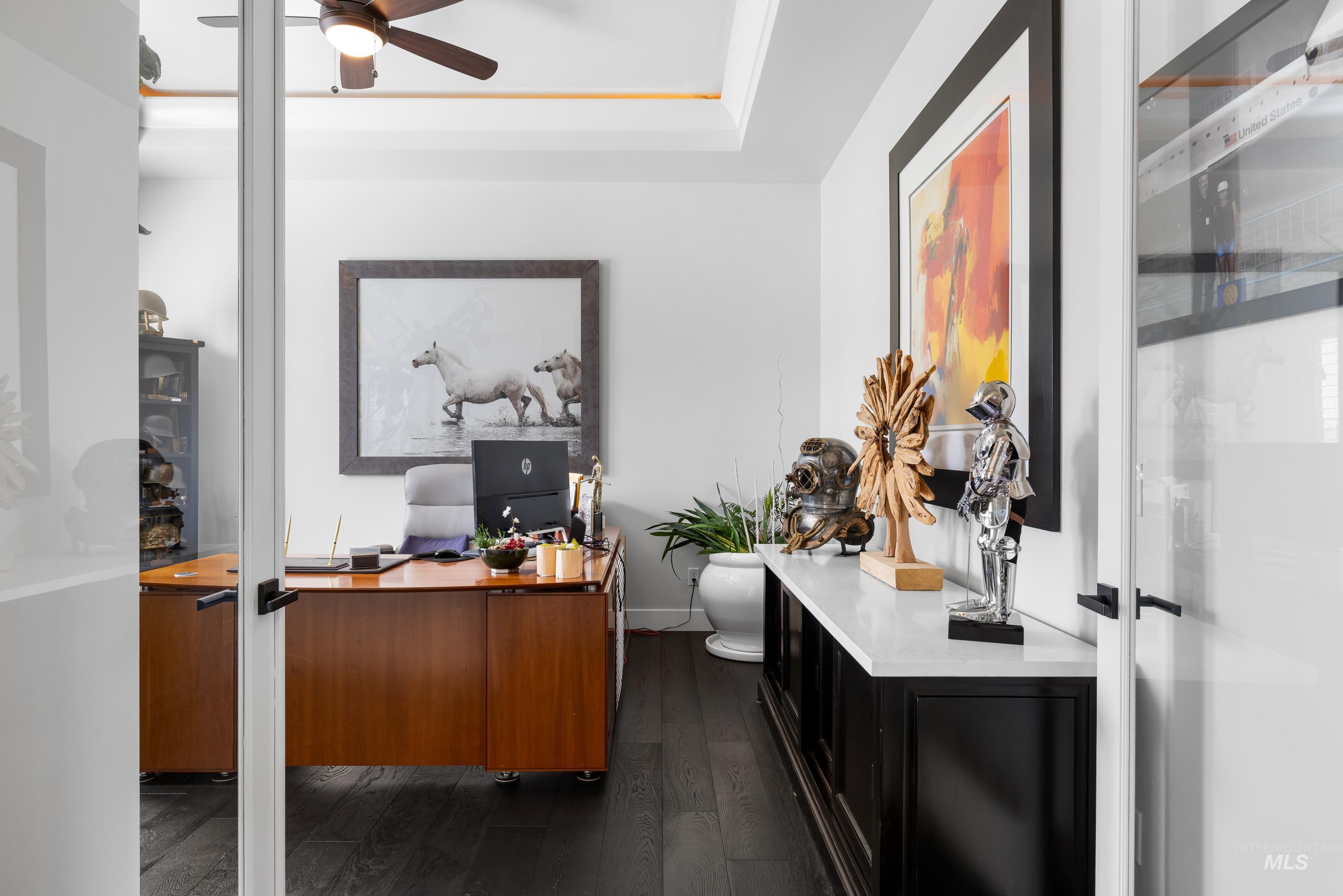 Office featuring dark wood-style floors, a raised ceiling, and a ceiling fan
