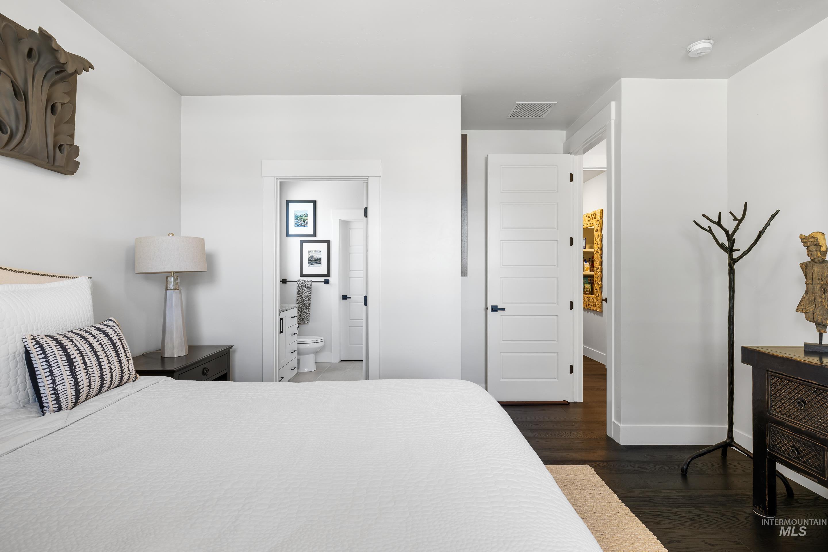 Bedroom featuring dark wood-style floors and ensuite bath