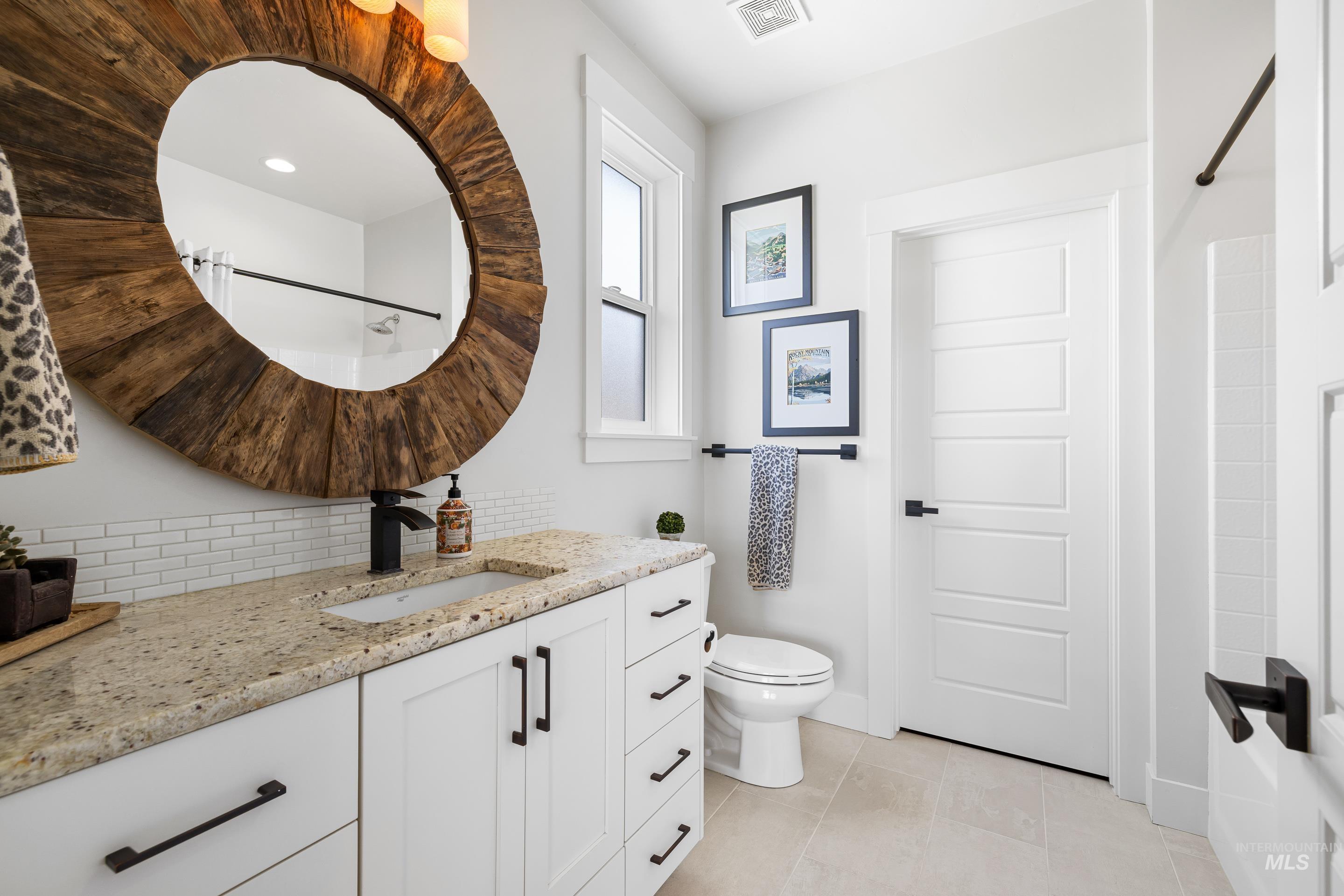 Full bath featuring vanity, decorative backsplash, and light tile patterned floors