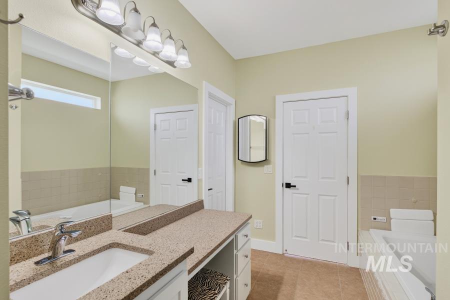 Bathroom with a bath, vanity, and light tile patterned flooring
