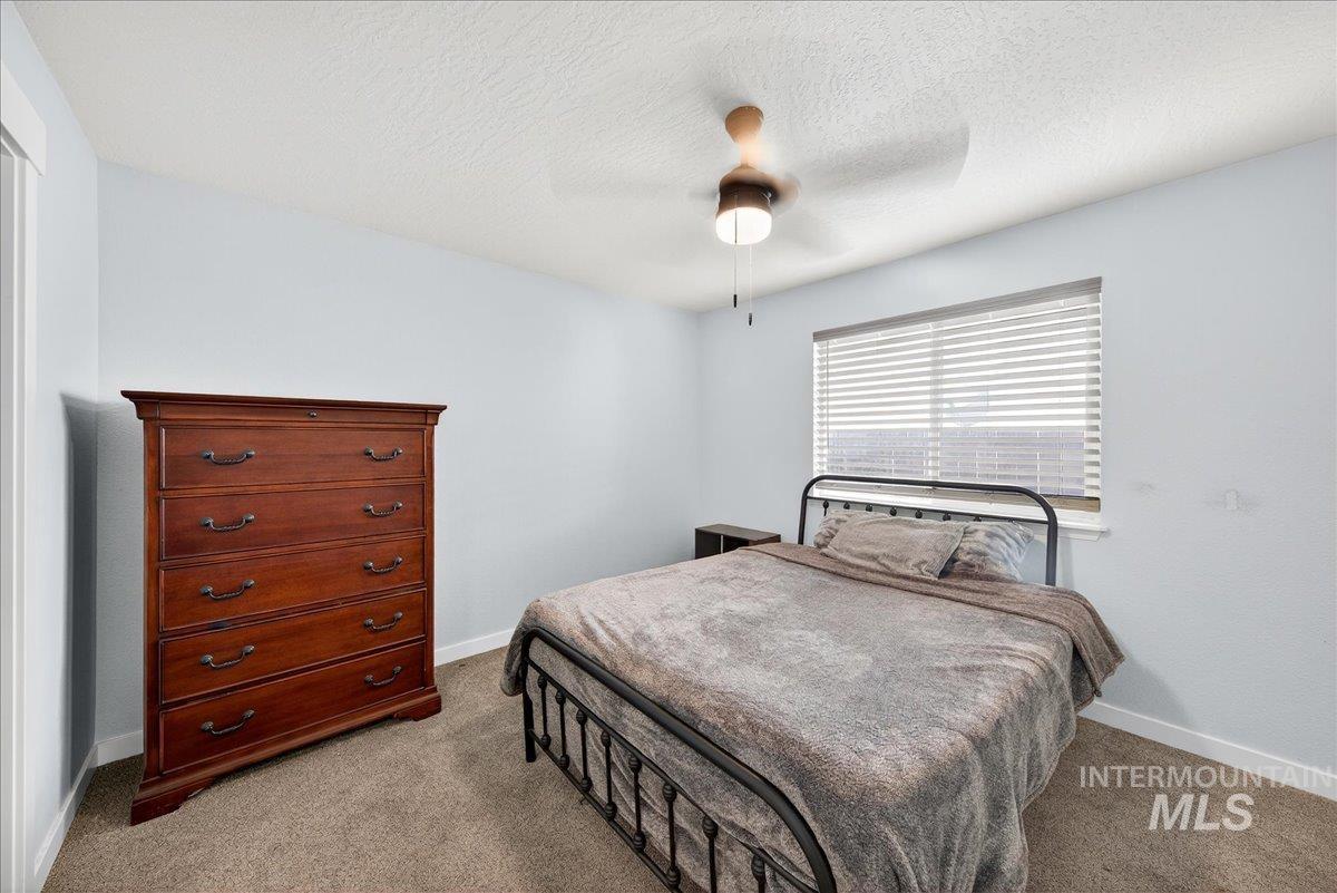 Bedroom featuring ceiling fan, carpet floors, and a textured ceiling
