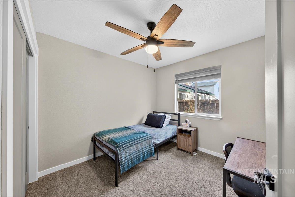 Bedroom featuring light carpet, a ceiling fan, and a textured ceiling