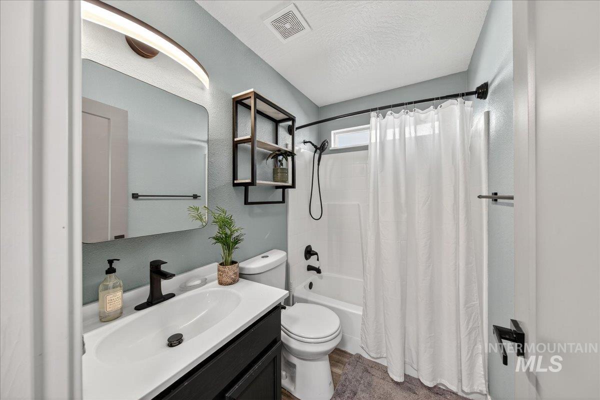 Full bath with shower / bath combo, vanity, and a textured ceiling