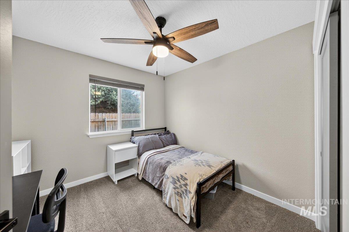 Carpeted bedroom featuring a textured ceiling and a ceiling fan