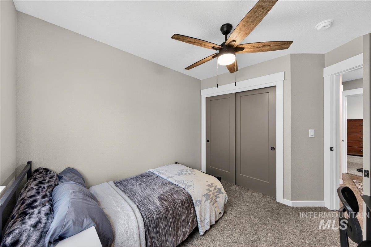 Carpeted bedroom featuring a ceiling fan and a closet