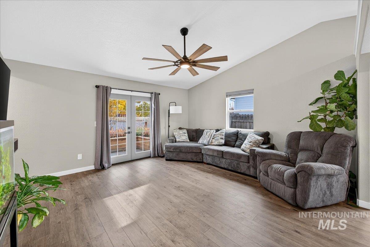 Living room with french doors, lofted ceiling, hardwood / wood-style flooring, and ceiling fan