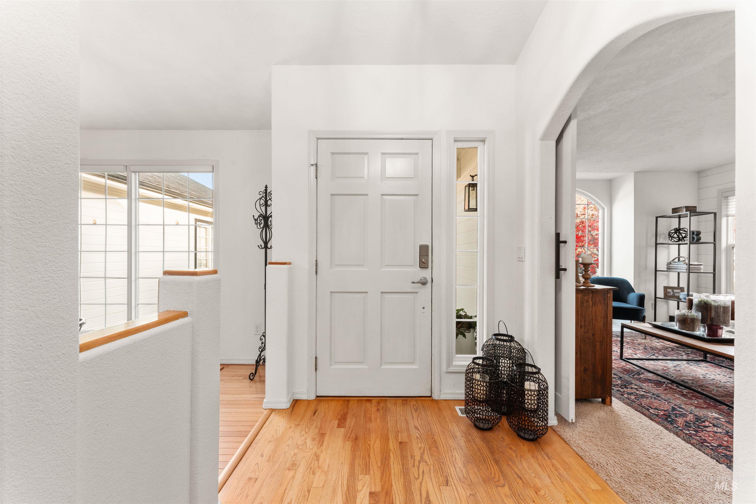 Entryway with light wood-type flooring and arched walkways