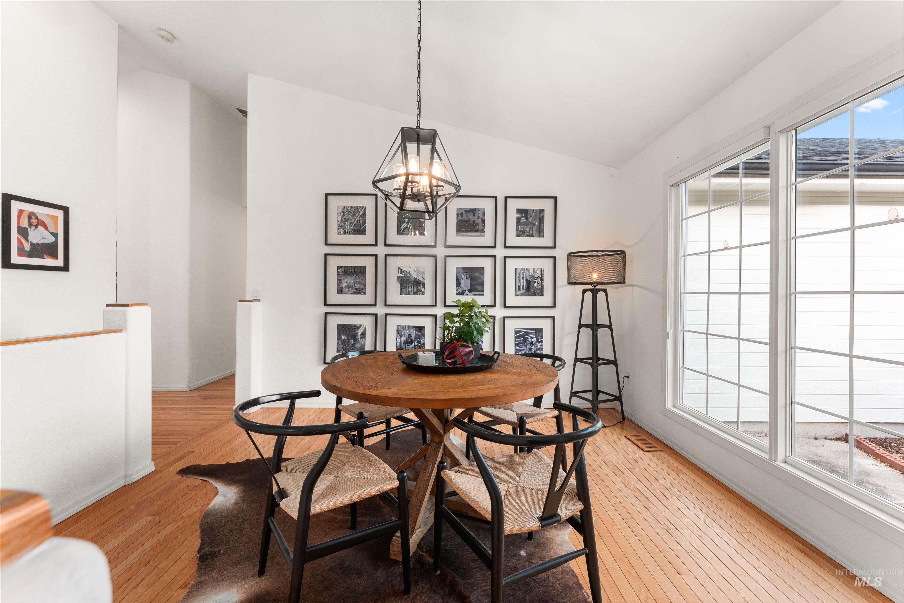 Dining room featuring vaulted ceiling, light wood-style floors, and a chandelier