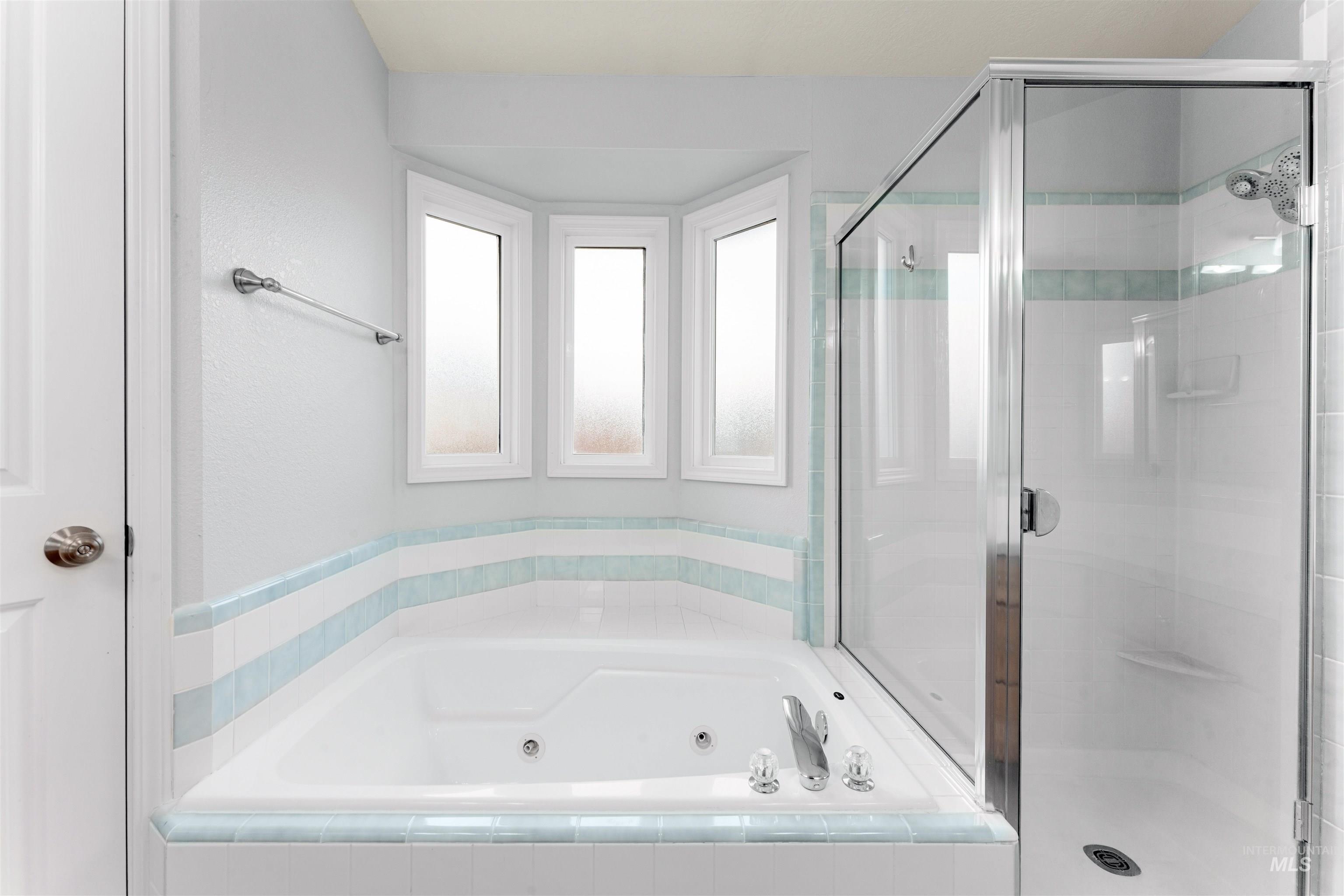 Full bath with a whirlpool tub and a stall shower