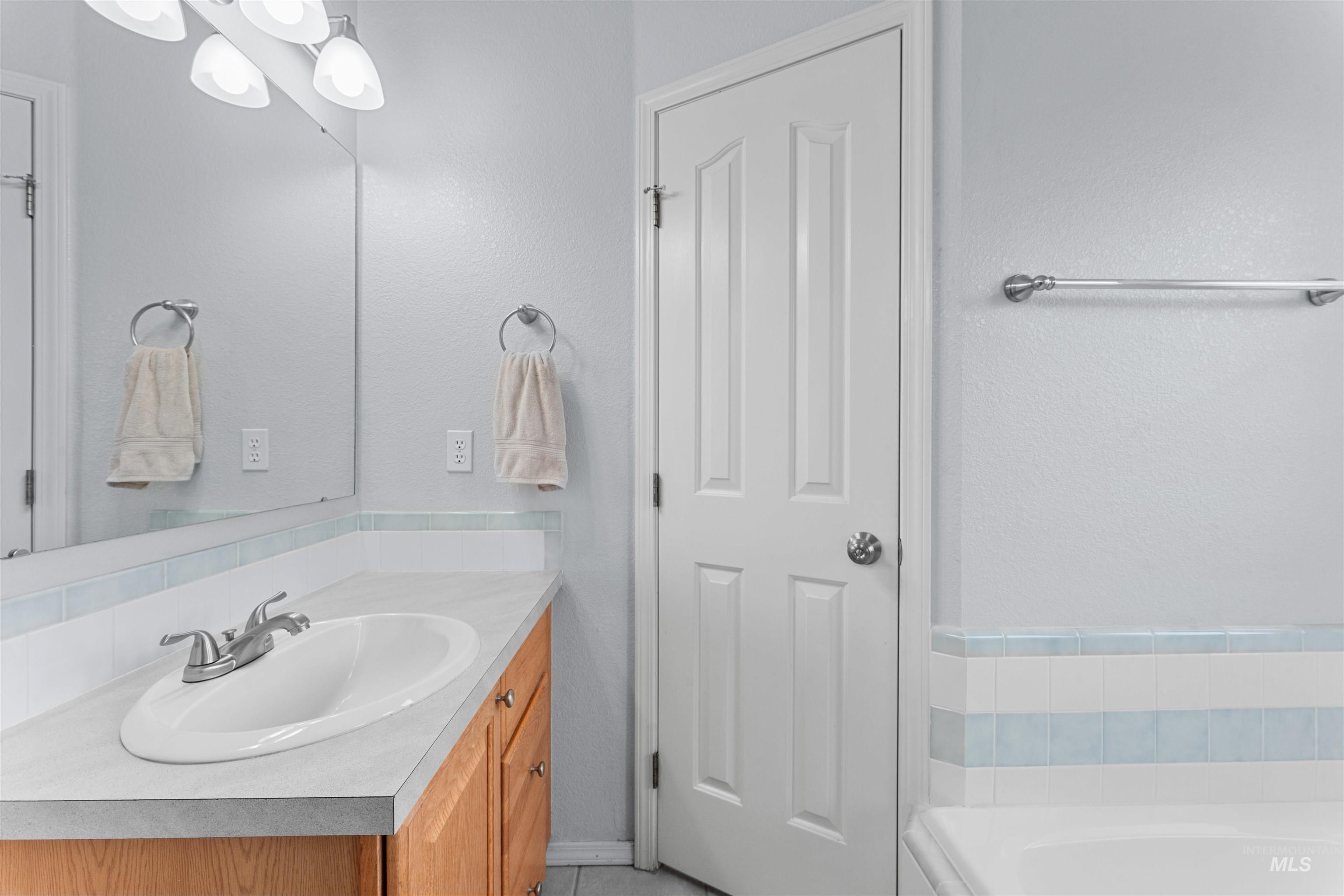 Full bath featuring vanity, a bathtub, and light tile patterned floors.