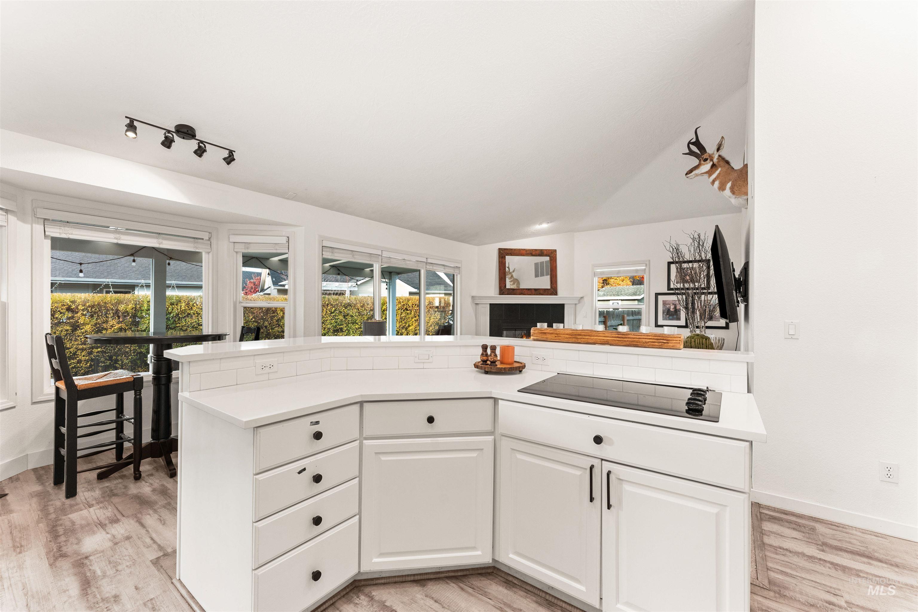 Kitchen with white cabinets, plenty of natural light, light wood-style floors, a kitchen island, and vaulted ceiling