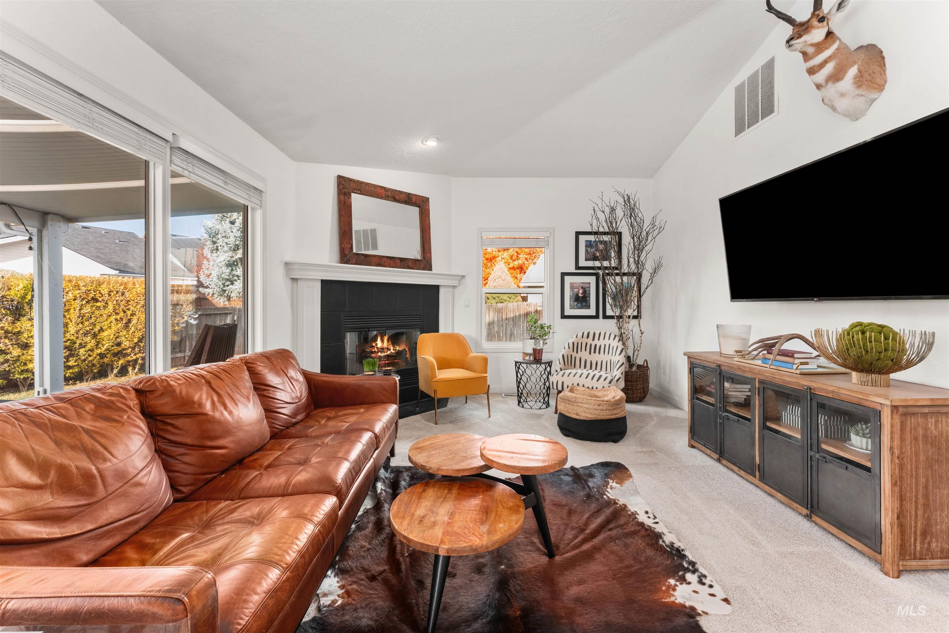 Living area with a fireplace, light colored carpet, vaulted ceiling, and recessed lighting