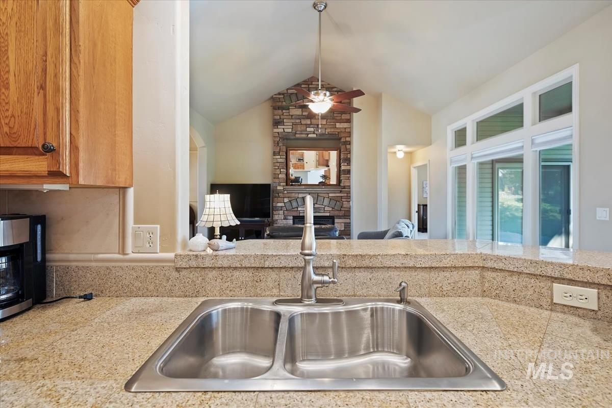Kitchen with vaulted ceiling, a fireplace, a ceiling fan, and open floor plan