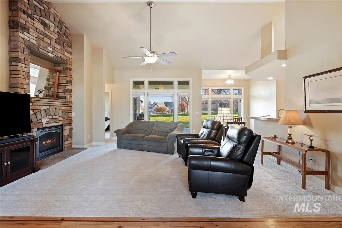 Carpeted living area with a fireplace, a towering ceiling, and ceiling fan