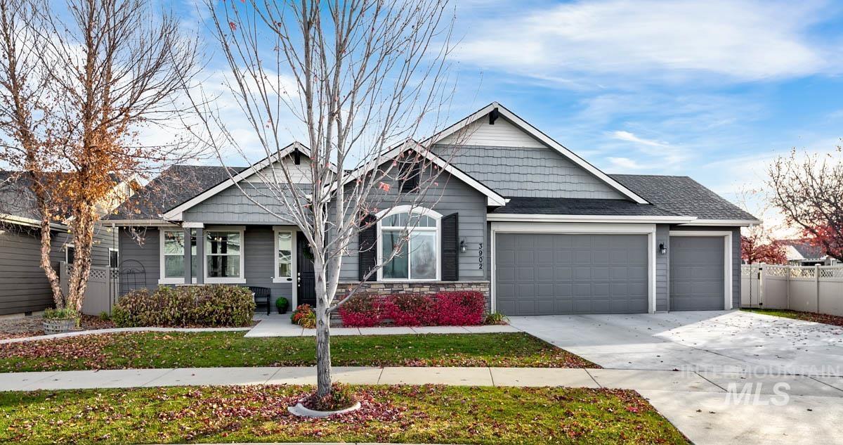 View of front facade with stone siding, an attached garage, concrete driveway, and a shingled roof