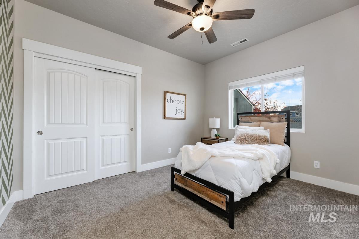 Carpeted bedroom with a closet and a ceiling fan