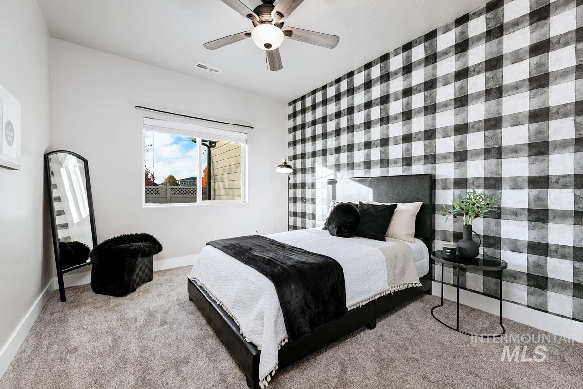 Carpeted bedroom featuring an accent wall and ceiling fan