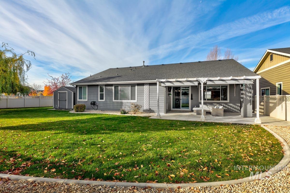 Back of house with a fenced backyard, a storage shed, a patio area, and a pergola