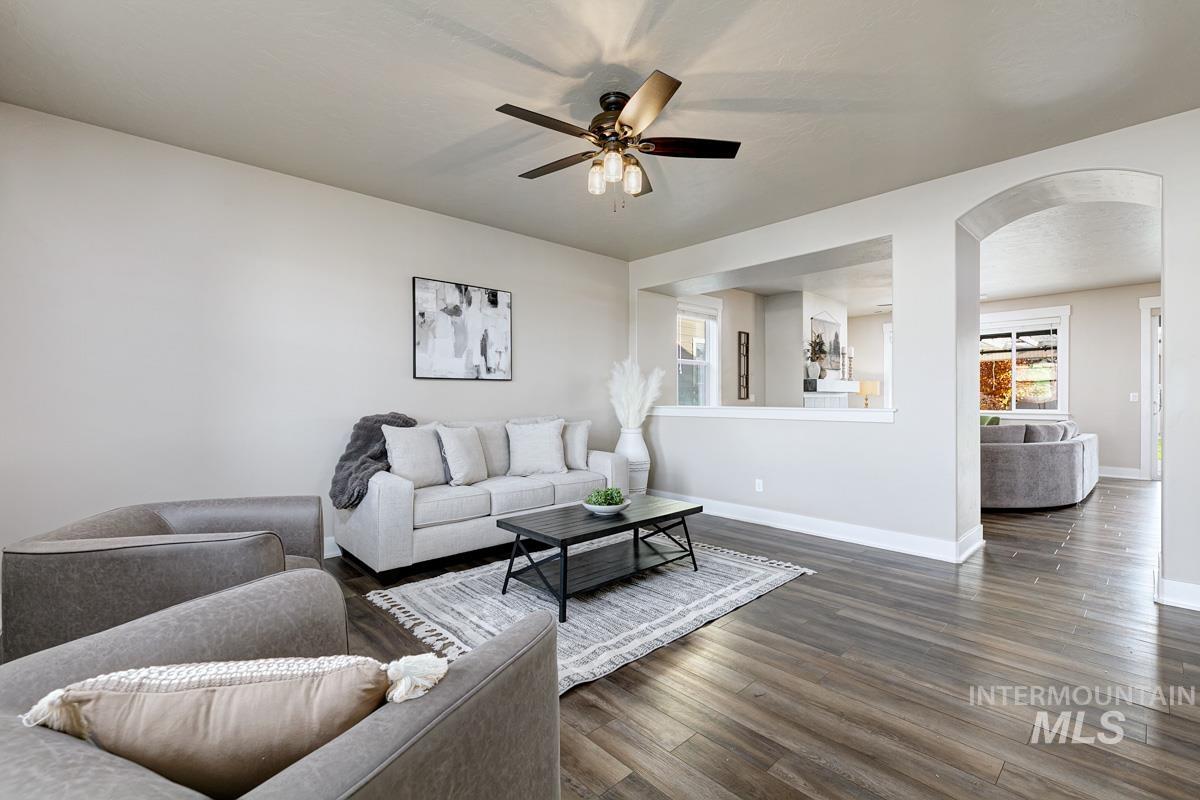 Living room featuring dark wood-type flooring, a ceiling fan, and arched walkways