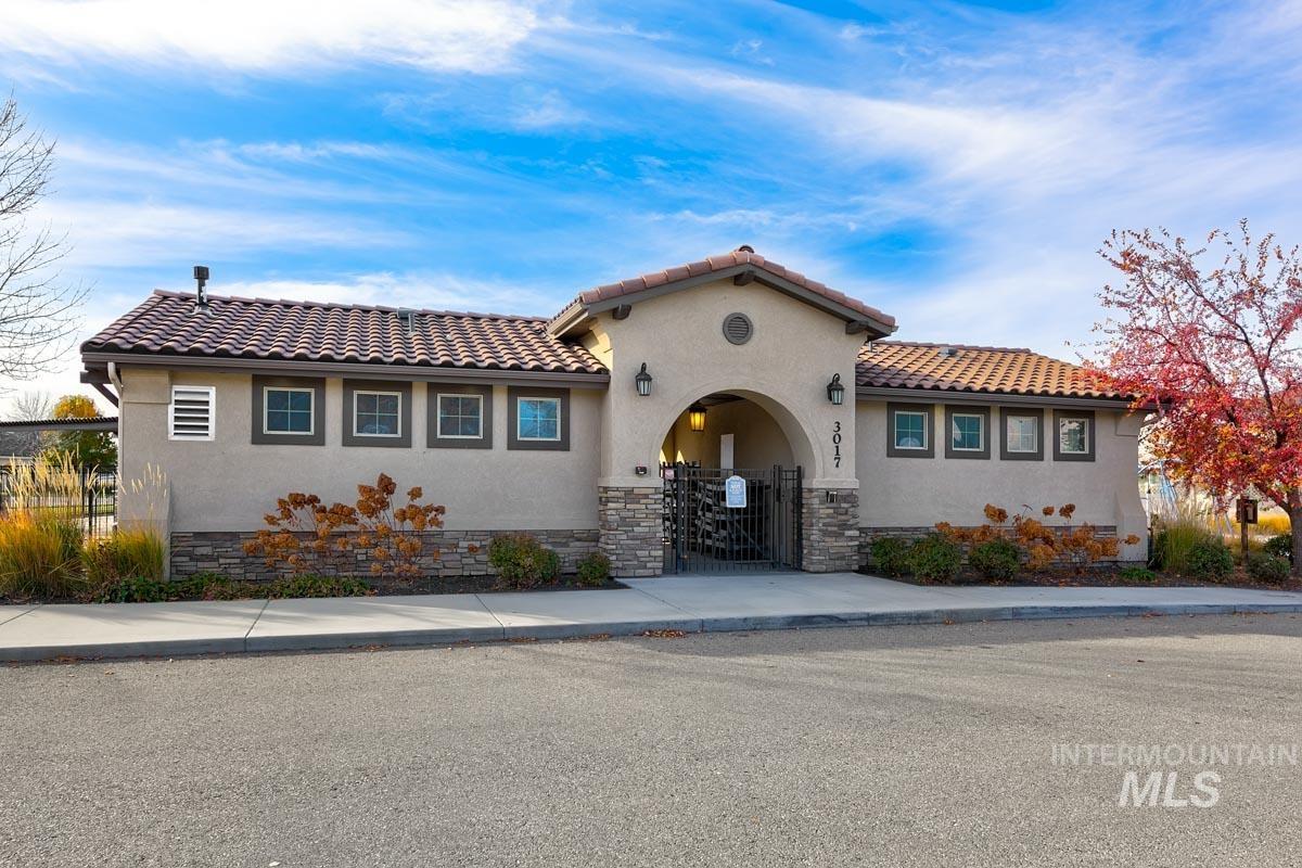 Mediterranean / spanish home with stucco siding, a fenced front yard, a gate, and stone siding