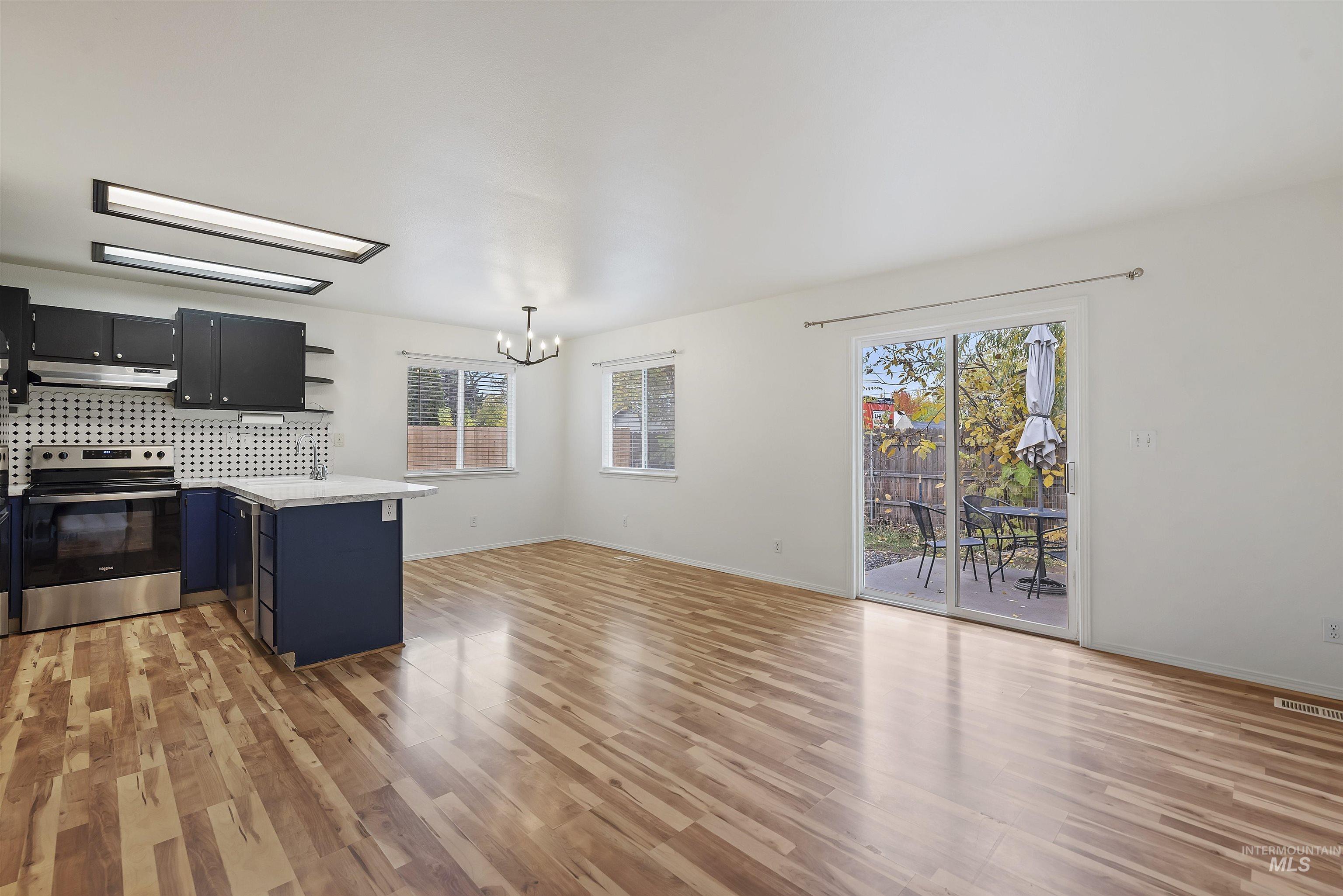Kitchen featuring open shelves, electric range, a peninsula, and light wood-style floors