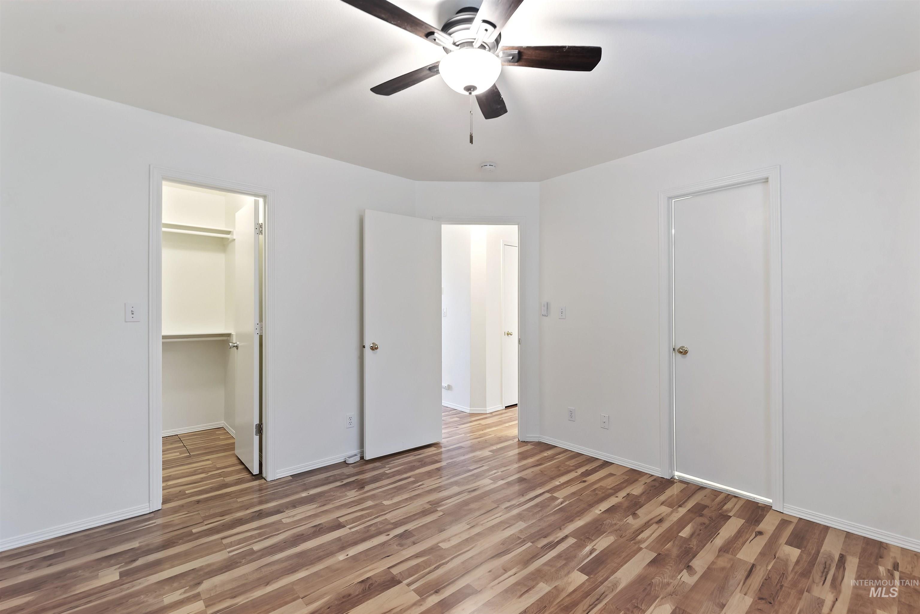 Unfurnished bedroom with light wood-style floors, a ceiling fan, and a spacious closet