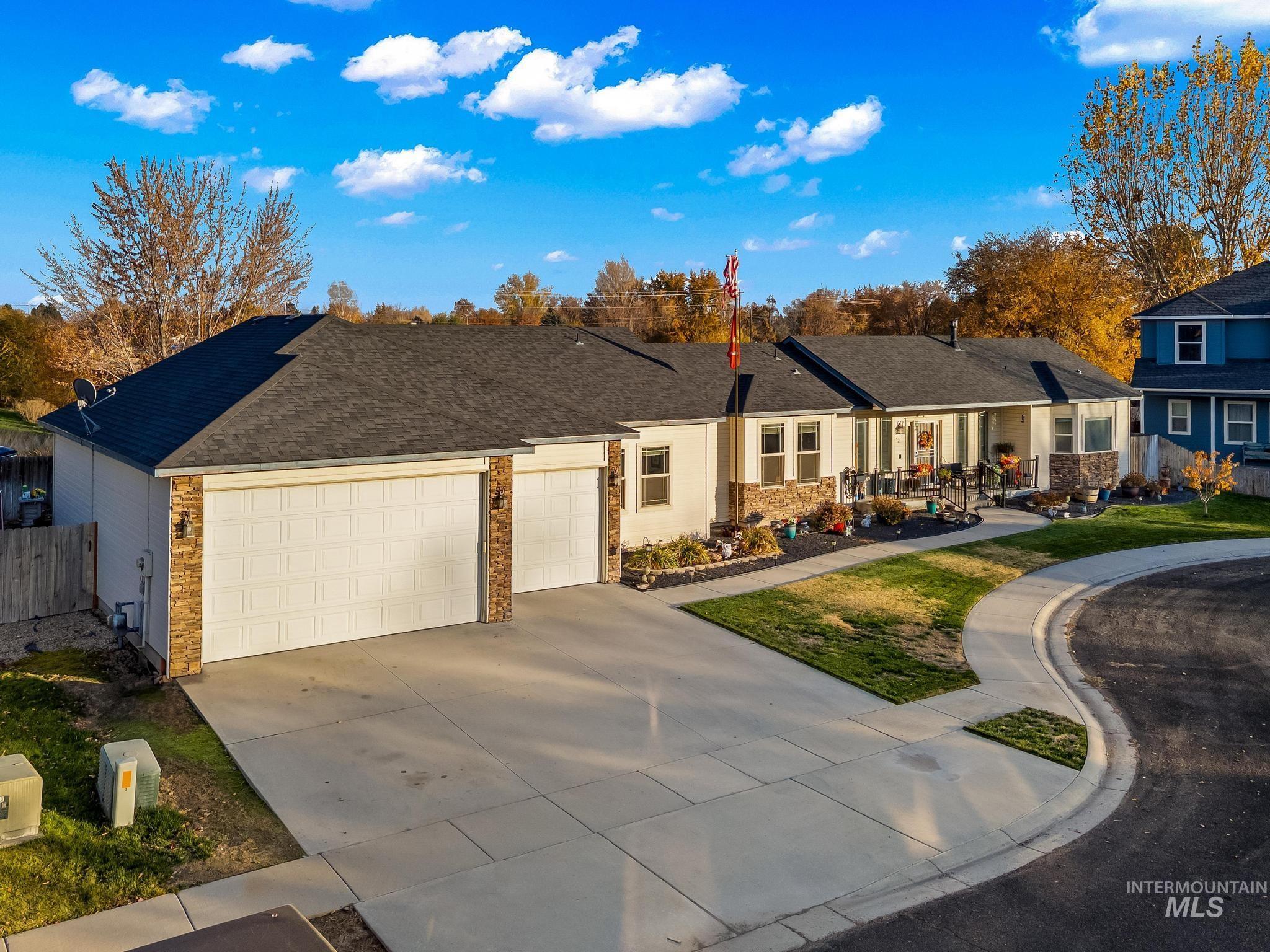 Ranch-style home featuring concrete driveway, brick siding, roof with shingles, a garage, and a residential view