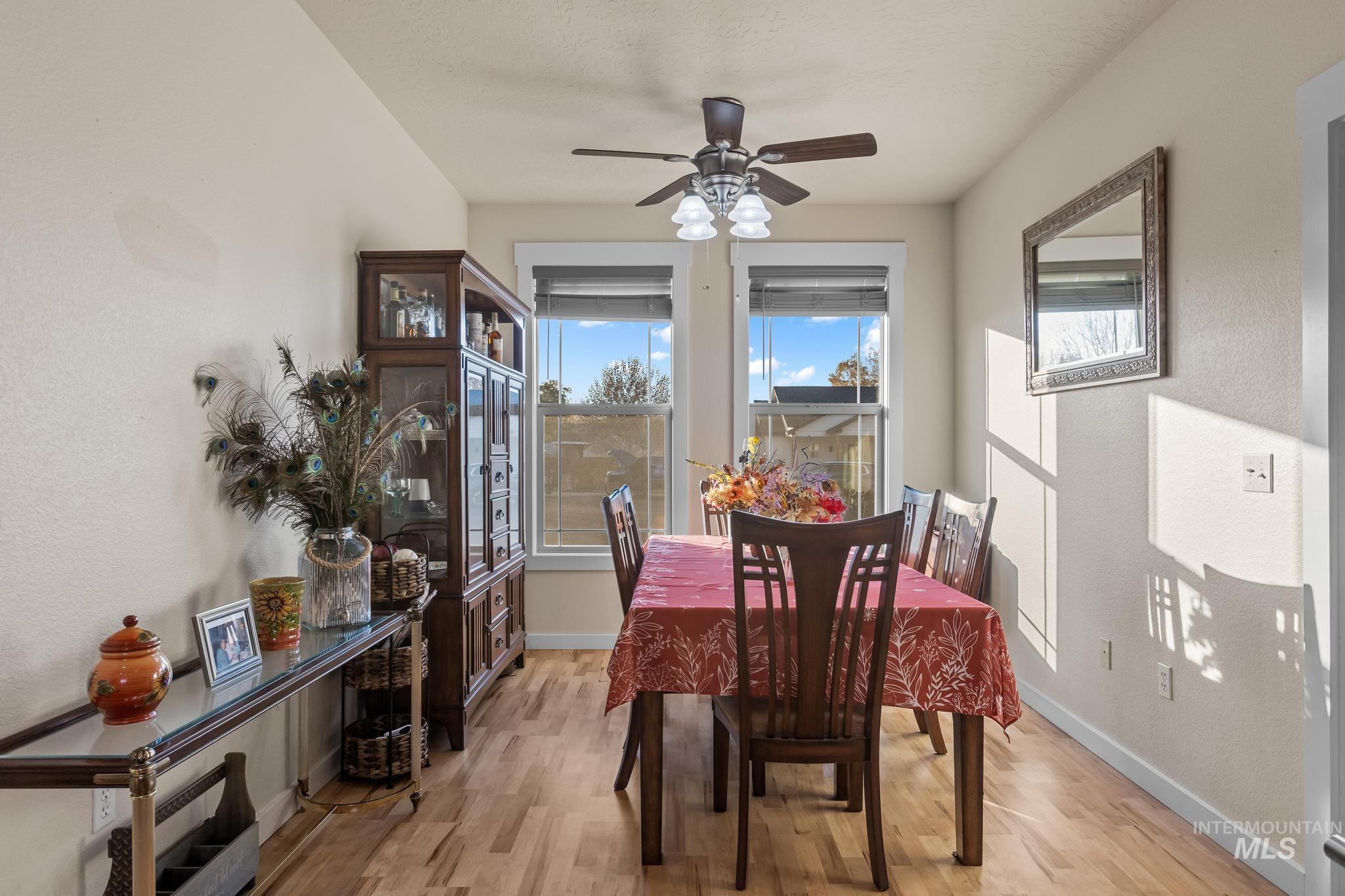 Dining room featuring light wood finished floors, a textured wall, and ceiling fan