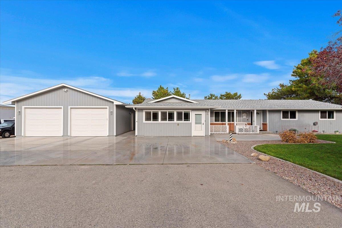 Ranch-style house with concrete driveway, a porch, roof with shingles, a front yard, and a garage