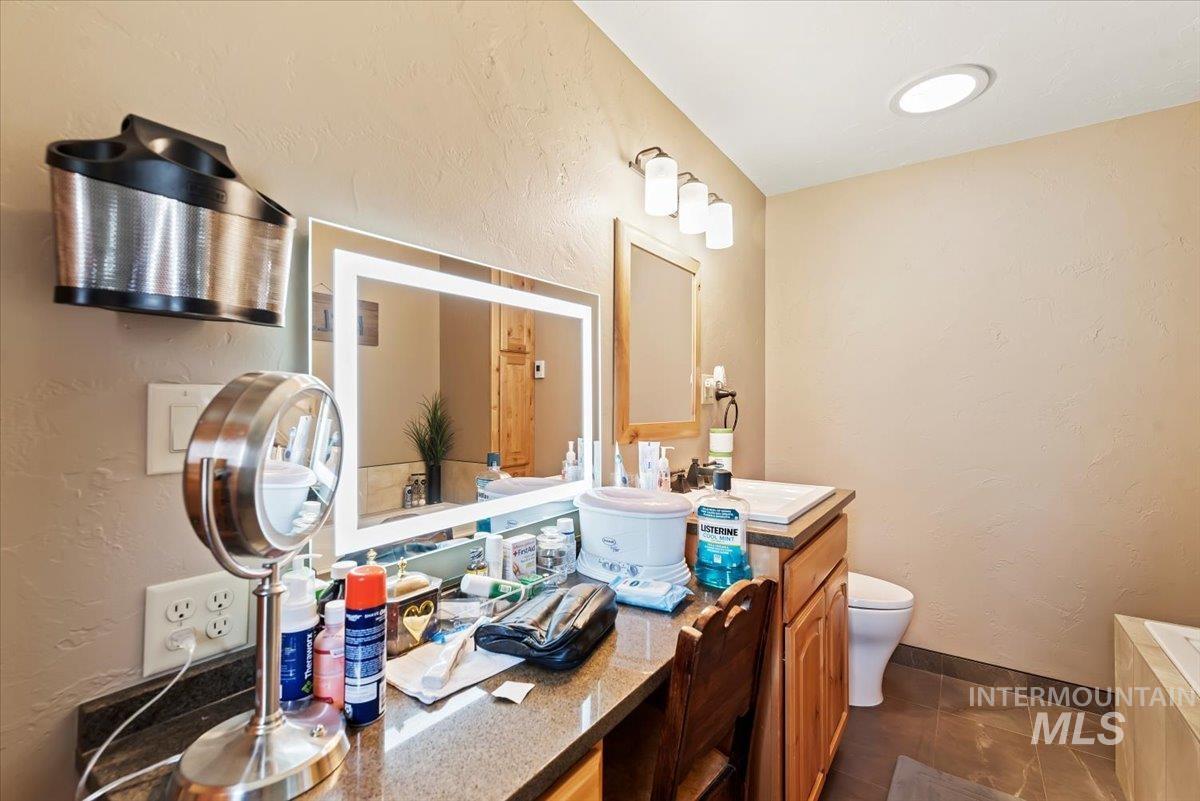 Bathroom featuring a textured wall, vanity, dark tile patterned flooring, and a bath