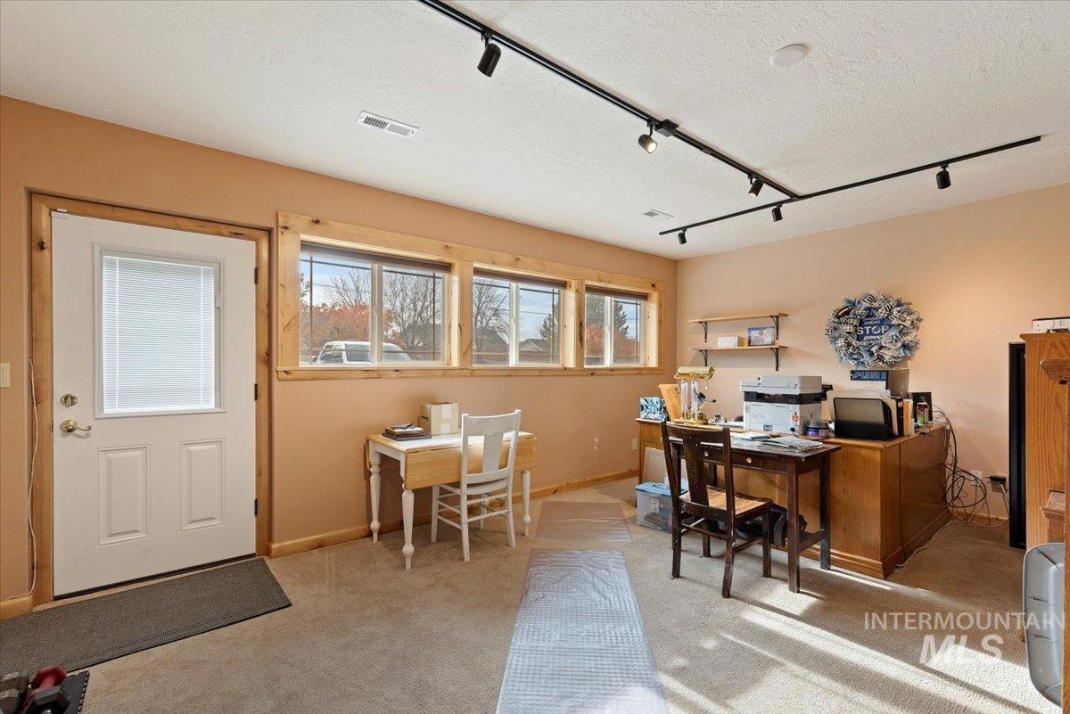 Home office with track lighting, light colored carpet, and a textured ceiling