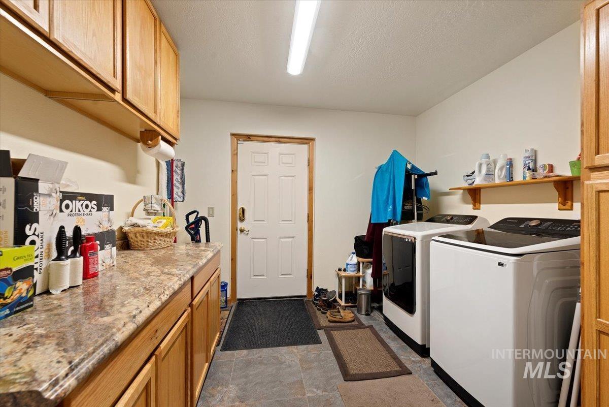 Washroom with cabinet space, separate washer and dryer, a textured ceiling, and dark stone finish floors